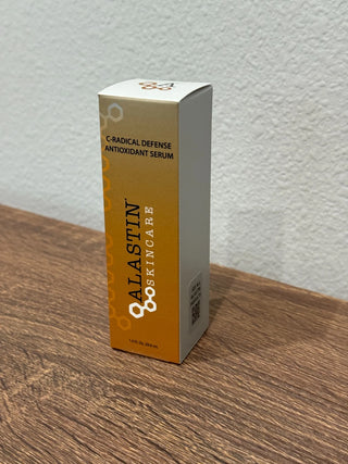 A box of Calastin Skincare C-Radical Defense Antioxidant Serum standing on a wooden surface against a textured white wall.