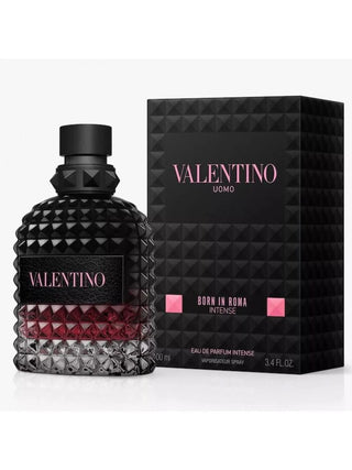 Valentino Uomo Born in Roma Intense Eau de Parfum Intense bottle with a textured black cap and base, showing a deep red liquid inside, next to its black geometric packaging box with pink lettering.