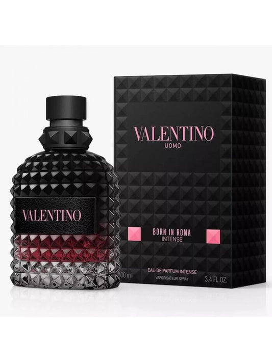 Valentino Uomo Born in Roma Intense Eau de Parfum Intense bottle with a textured black cap and base, showing a deep red liquid inside, next to its black geometric packaging box with pink lettering.